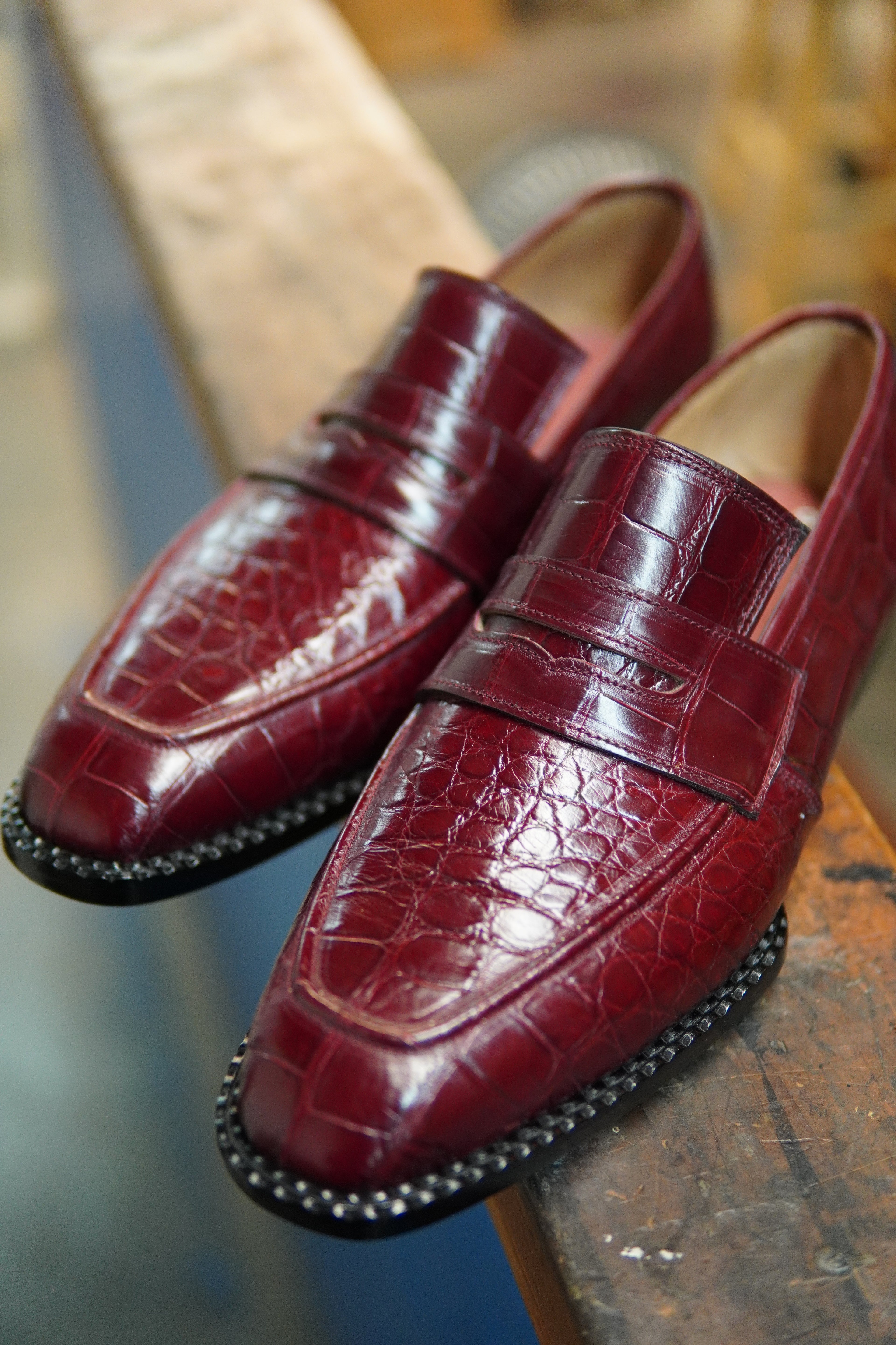 Pair of maroon leather loafers on a wooden surface with a blurred background