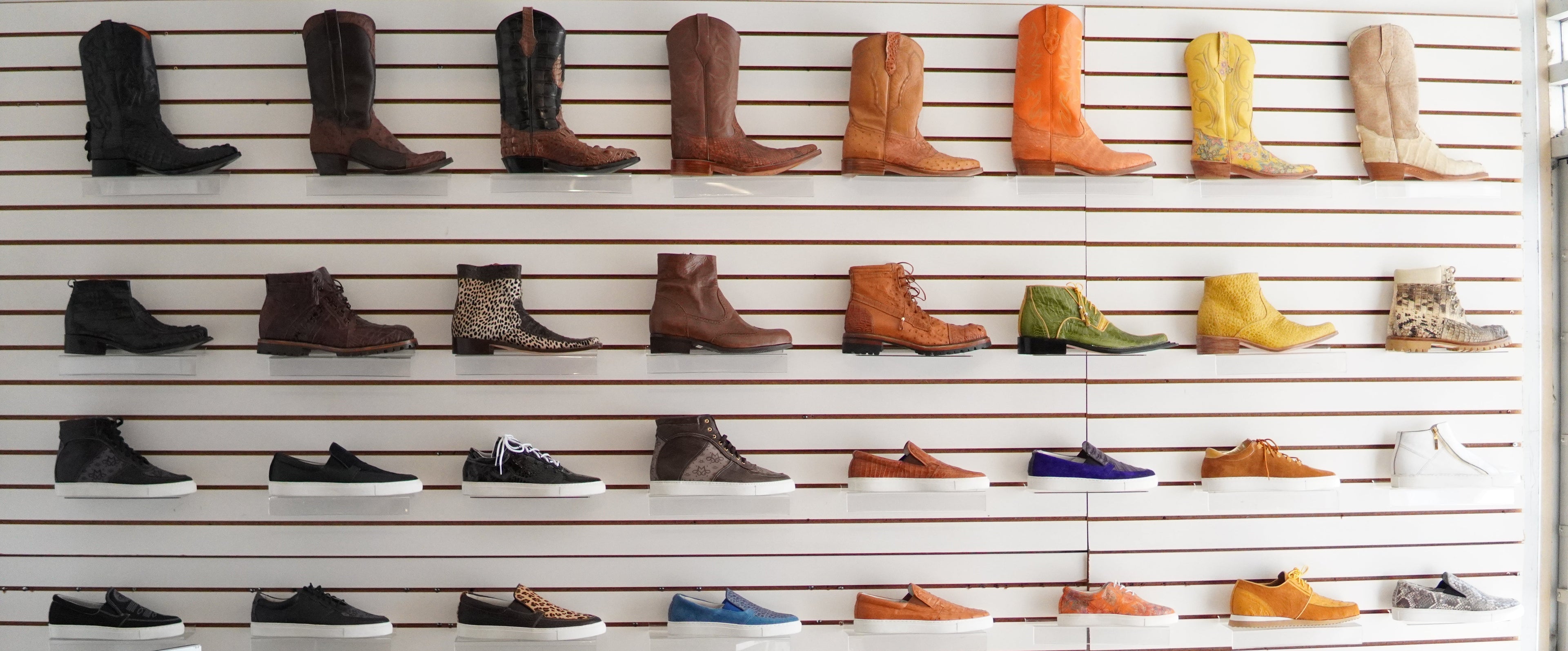 Wall display of various boots and shoes in a store setting.